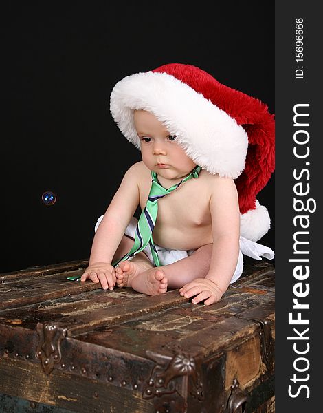 Cute christmas baby boy sitting on an antique trunk