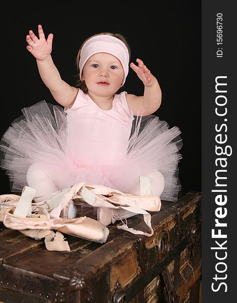 Baby ballerina sitting on an antique trunk. Baby ballerina sitting on an antique trunk