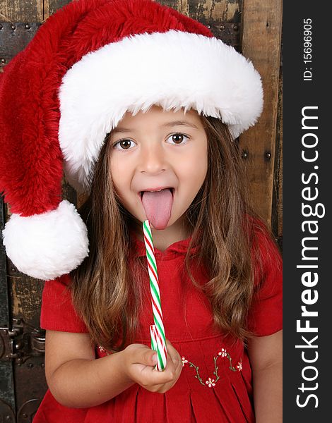 Cute brunette girl eating Christmas candy and sticking her tongue out