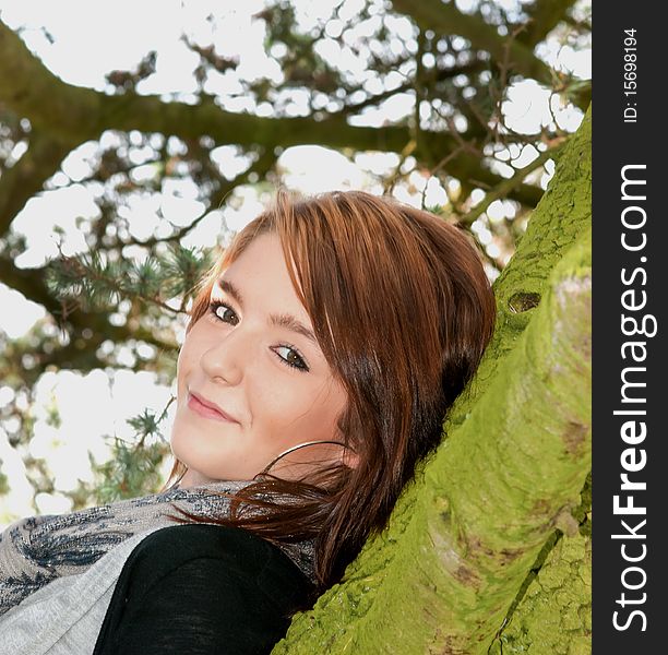 A teenage girl leaning on a tree. A teenage girl leaning on a tree
