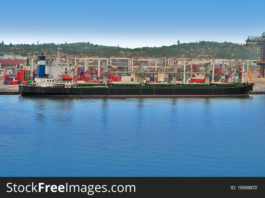 Huge container ship docked in harbor with containers in background. Huge container ship docked in harbor with containers in background