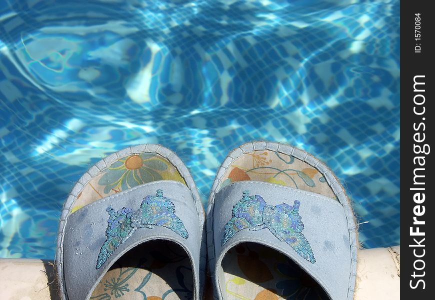 Pair of blue flip-flops by the swimming pool