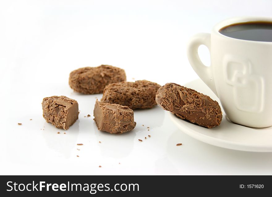 Single cup of coffee with chocolate treats on a white surface