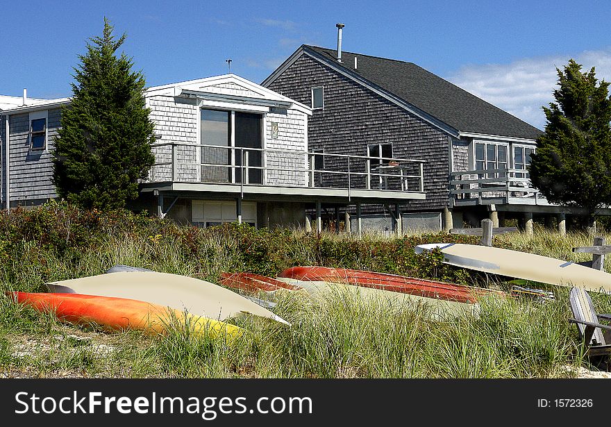 Summer cottages facing towards the ocean with boats and other watercrafts beached on the sand. Summer cottages facing towards the ocean with boats and other watercrafts beached on the sand