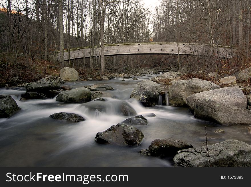 This is a picture of a wooden bridge crossing over a flowing stream in the Virginia countryside. This is a picture of a wooden bridge crossing over a flowing stream in the Virginia countryside.