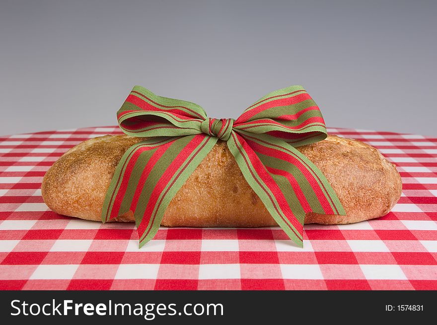 Fresh baked loaf of bread with ribbon on a red and white checkerboard cloth. Fresh baked loaf of bread with ribbon on a red and white checkerboard cloth