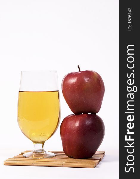 Two apples stacked beside a glass of beer
