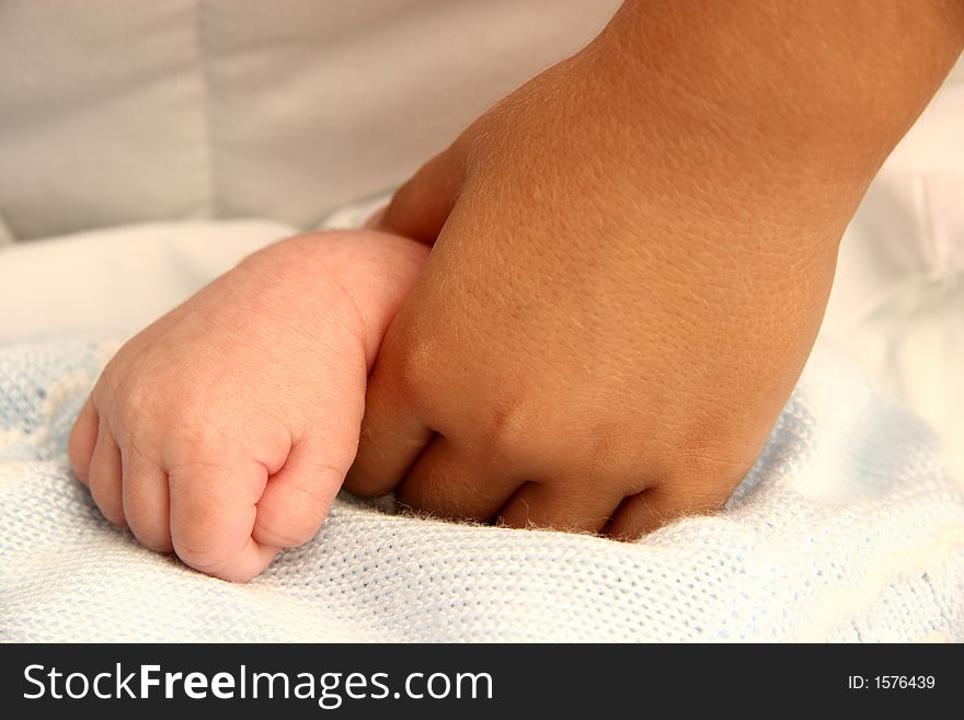 A little girl is holding the hand of her new born brother. A little girl is holding the hand of her new born brother
