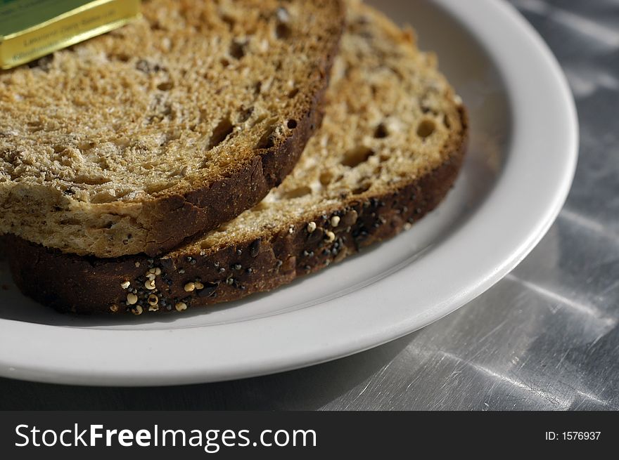 Detail of whole wheat seeded sliced bread toasted on a white plate on a cafe table. Detail of whole wheat seeded sliced bread toasted on a white plate on a cafe table