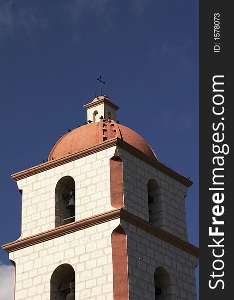 Redish spire of a church with cross on top before blue clear sky. Redish spire of a church with cross on top before blue clear sky