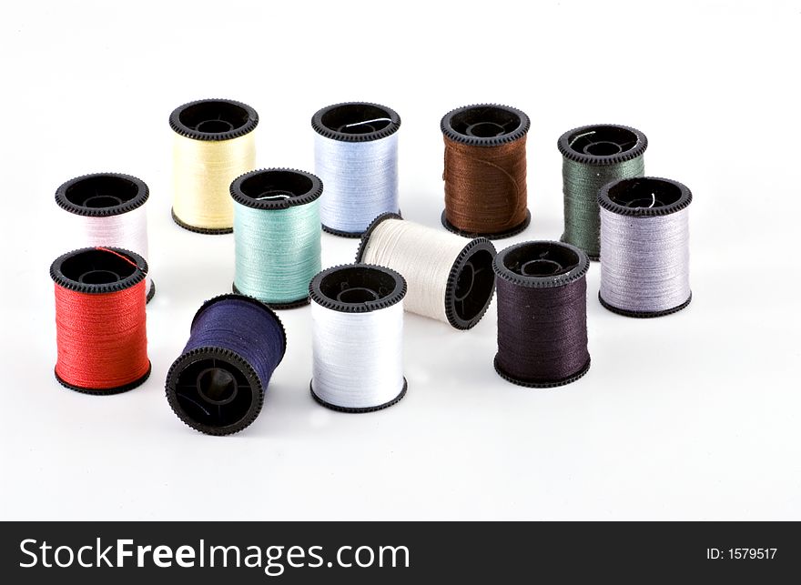 Isolated shot of a dozen spools of multi colored thread. Isolated shot of a dozen spools of multi colored thread