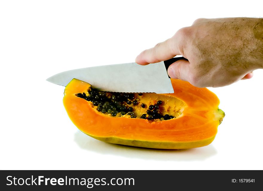 Isolated shot of a papaya being cut with a large knife. Isolated shot of a papaya being cut with a large knife