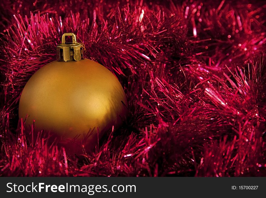 One single gold christmas decoration ball on red tinsel