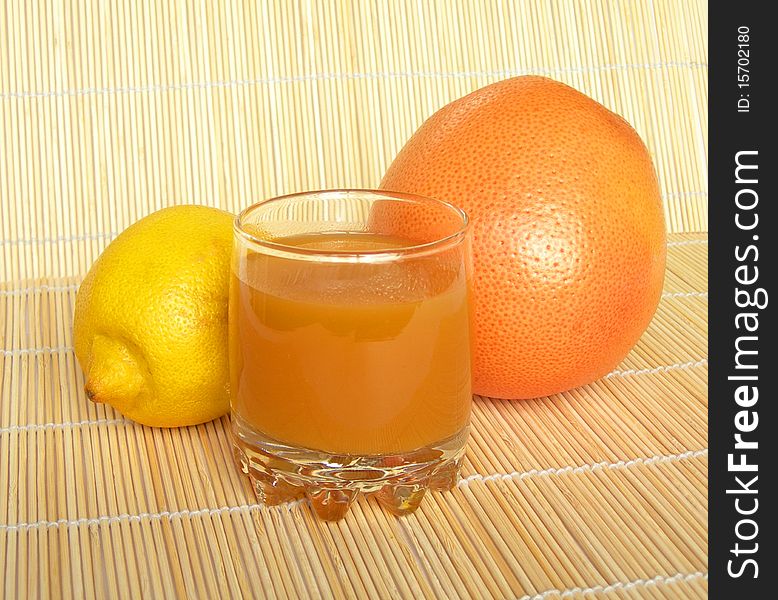 Grapefruit, lemon and a glass of juice are shown in the picture. Grapefruit, lemon and a glass of juice are shown in the picture.