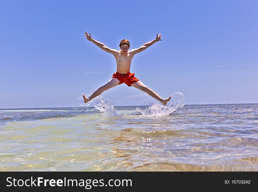 Boy enjoys the wonderful clear ocean and jumps atthe sandbank out of the water