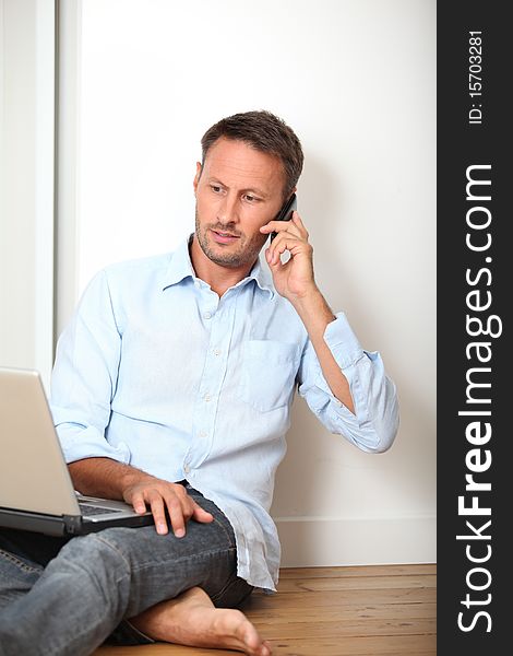 Man sitting on the floor at home with laptop computer. Man sitting on the floor at home with laptop computer