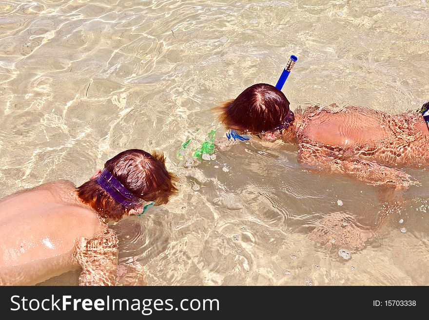 Boys are diving and snorkeling together in the clear ocean. Boys are diving and snorkeling together in the clear ocean