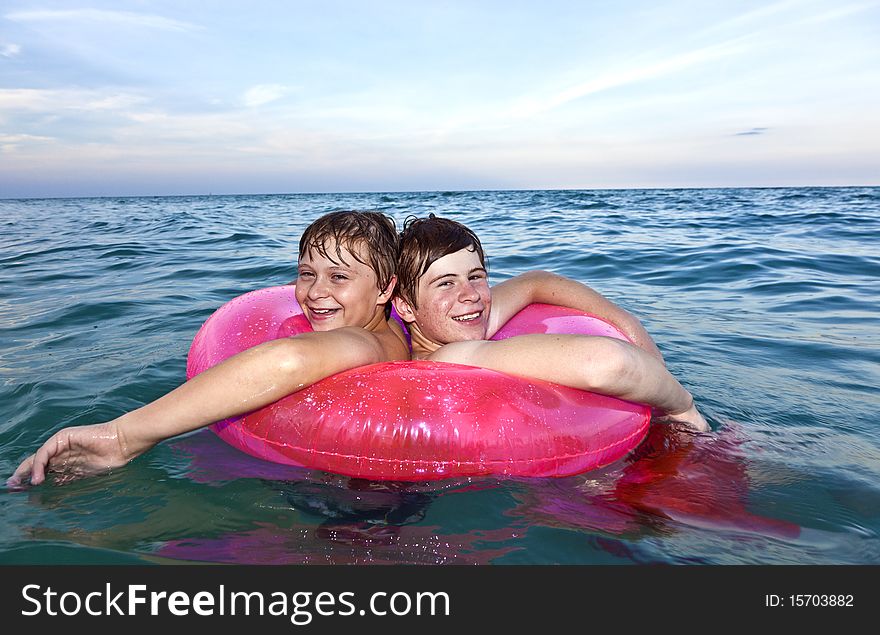 Brothers in a swim ring have fun in the ocean