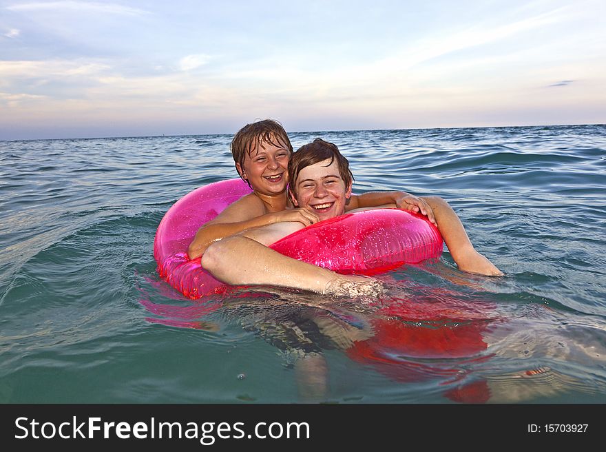 Two brothers in a swim ring have fun in the ocean