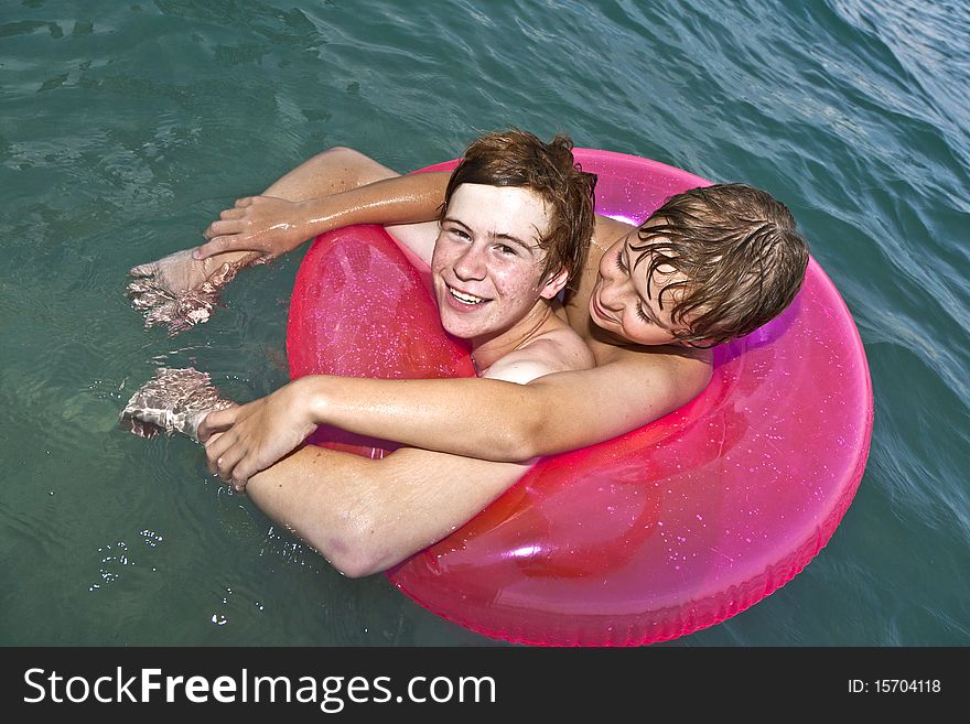 Two brothers in a swim ring have fun in the ocean