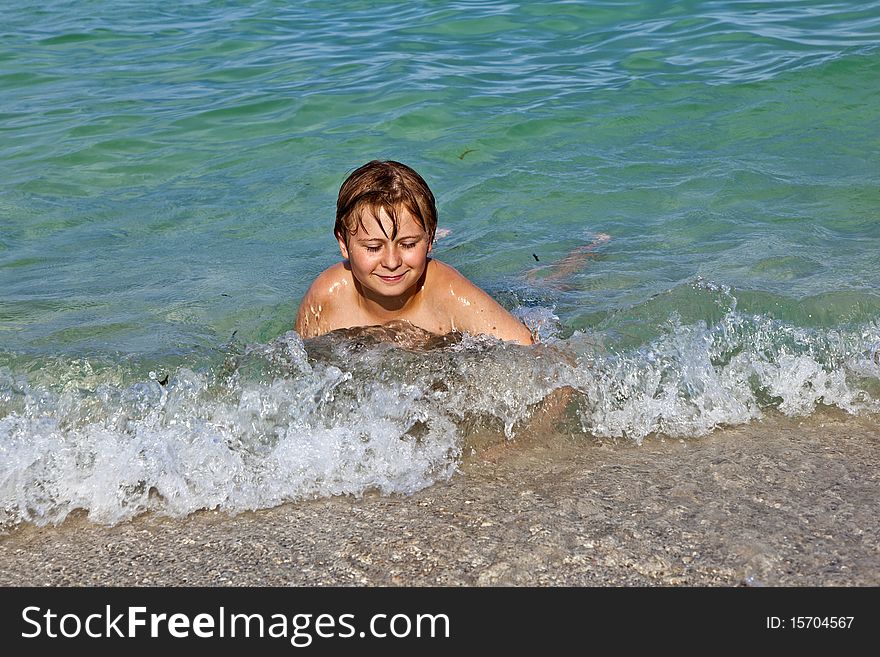 Boy lying in the surf enjoys the crystal clear water in the ocean. Boy lying in the surf enjoys the crystal clear water in the ocean