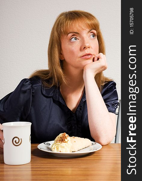 A vertical image of a pretty young woman in a cafe setting having lunch of coffee and a delicious cream cake. A vertical image of a pretty young woman in a cafe setting having lunch of coffee and a delicious cream cake
