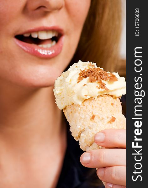 A vertical image of a pretty young woman in a cafe setting eating a delicious cream cake. A vertical image of a pretty young woman in a cafe setting eating a delicious cream cake