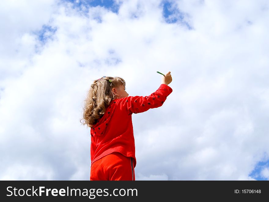 The girl in red clothes draws a pencil in the sky with clouds. The girl in red clothes draws a pencil in the sky with clouds