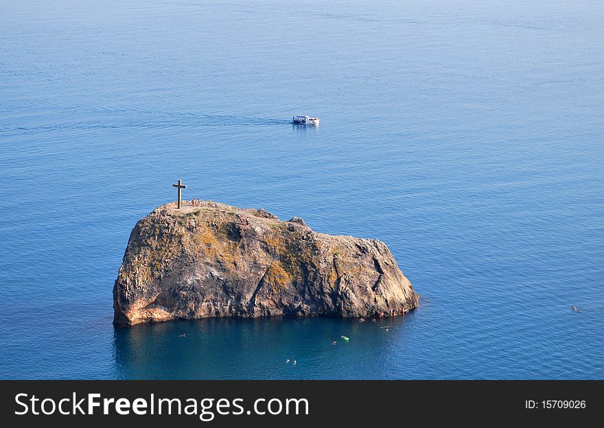 Wooden cross standing on a rock on the middle of the sea. Wooden cross standing on a rock on the middle of the sea.