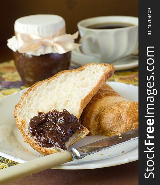 Croissant with chocolate cream and jar of chocolate  cream and coffee