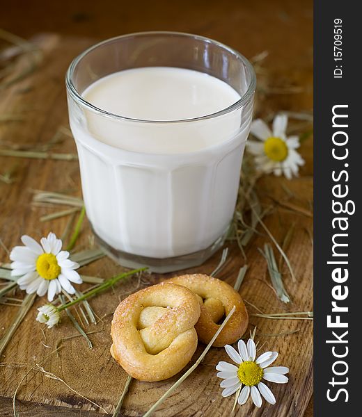 Glass of milk on a board with two pretzels and chamomile