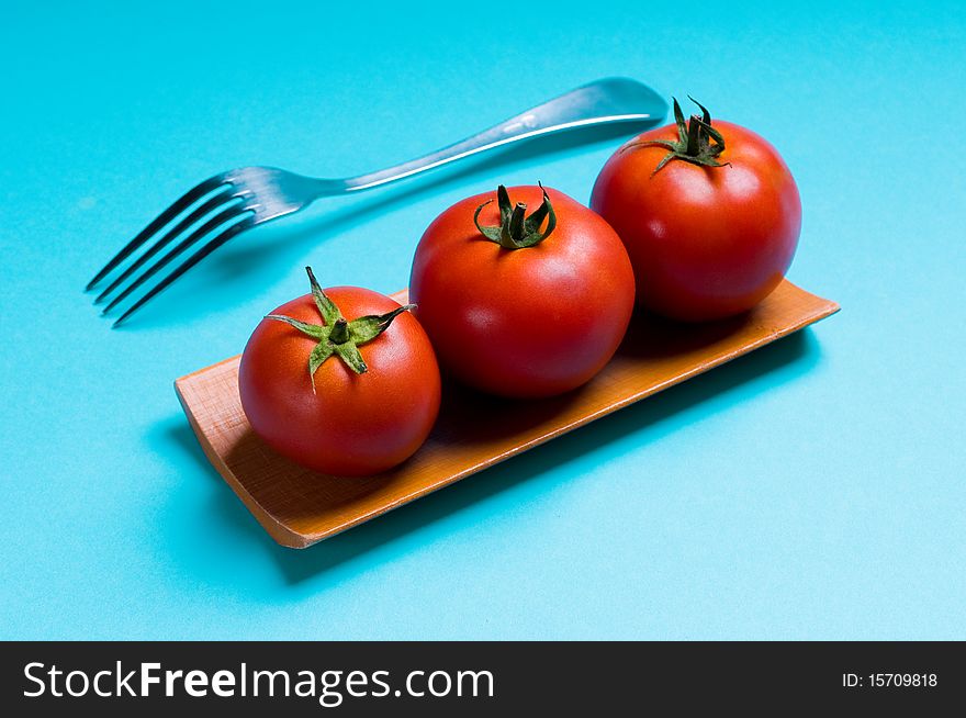 Ripe tomatoes and plug on blue background