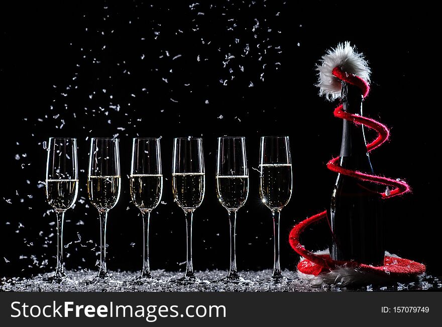 Champagne glasses set on black background with snow, alcohol, beverage, bottle, bubbles, catering, celebrate, celebration, cheers, christmas, closeup, cork, drink, fizz, gold, holiday, isolated, liquid, luxury, new, year, party, popping, restaurant, santa, serving, silhouette, splash, toast, white, wine. Champagne glasses set on black background with snow, alcohol, beverage, bottle, bubbles, catering, celebrate, celebration, cheers, christmas, closeup, cork, drink, fizz, gold, holiday, isolated, liquid, luxury, new, year, party, popping, restaurant, santa, serving, silhouette, splash, toast, white, wine