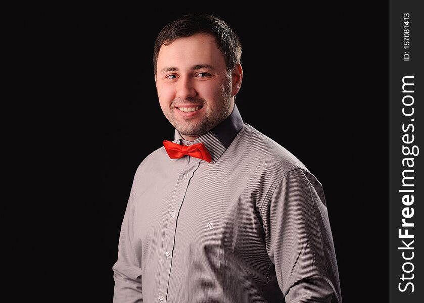 smiling man with red butterfly tie over black background, adult, beard, beauty, bow, bowtie, brown, business, ceremony, classic, closeup, clothes, clothing, dinner, dress, elegance, elegant, evening, face, fashion, garment, guy, happy, hipster, holiday, jacket, luxury, male, modern, object, person, portrait, retro, shirt, smile, style, suit, symbol, textile, traditional, uniform, waiter, well, white, young