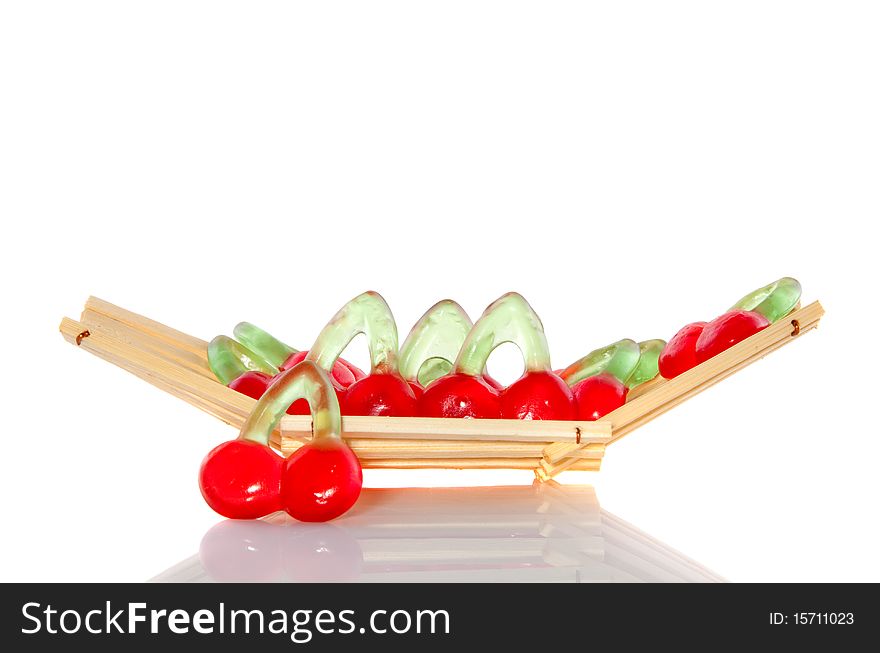 Candy in the form of sweet cherries in a wooden tray isolated over white. Candy in the form of sweet cherries in a wooden tray isolated over white