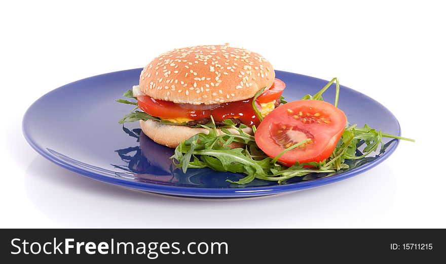 A close-up of a a fresh hamburger with cheese and salad on a blue plate  isolated over white. A close-up of a a fresh hamburger with cheese and salad on a blue plate  isolated over white