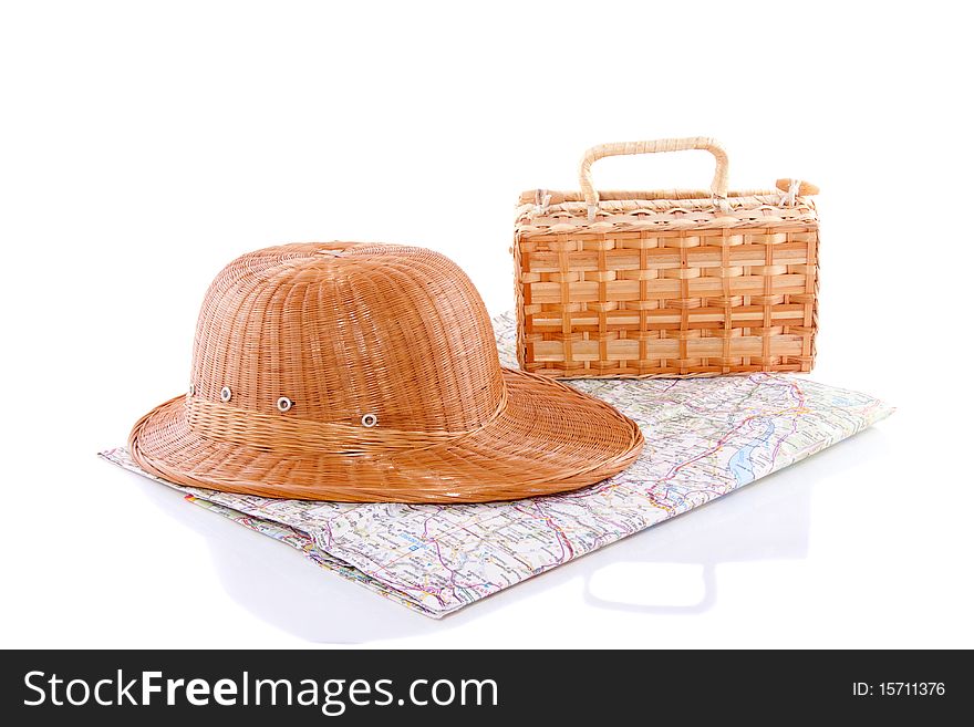 A straw hat and a wicker trunk on a map isolated over white. A straw hat and a wicker trunk on a map isolated over white