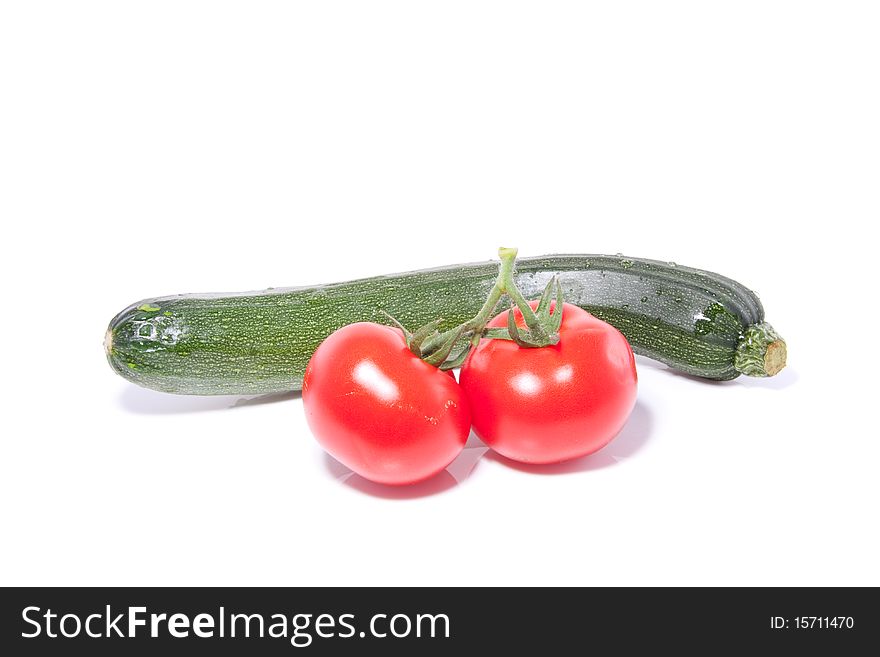 A green courgette with two tomatoes isolated over white