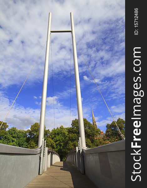 Modern pedestrian suspension bridge against a blue sky