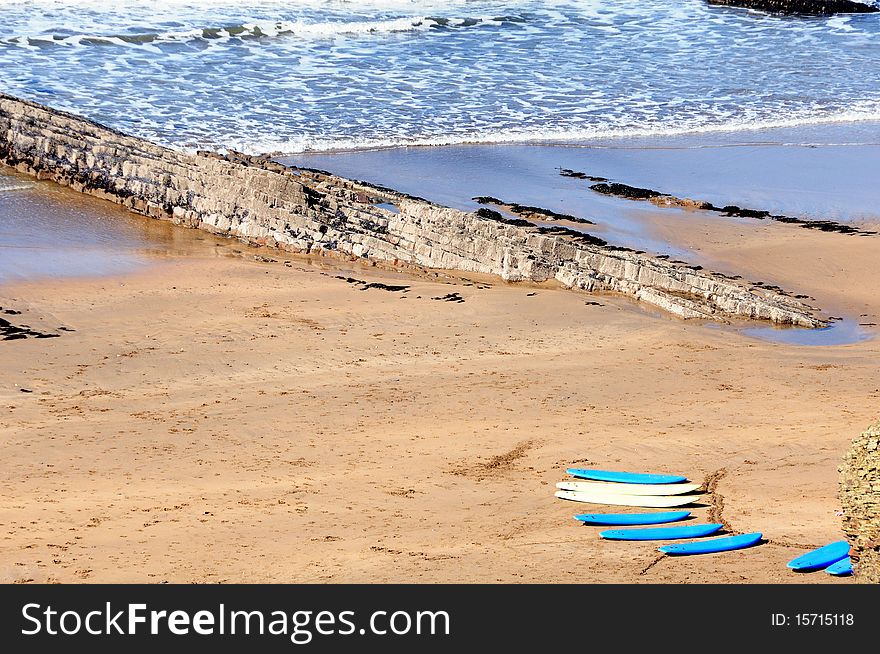 Surf boards on a sandy beach with a break wall on the Cornwall Coast. Surf boards on a sandy beach with a break wall on the Cornwall Coast