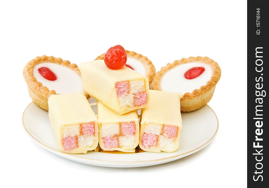 Plate with delicious cakes, cupcakes and cherry on top. Isolated over white background. Plate with delicious cakes, cupcakes and cherry on top. Isolated over white background.