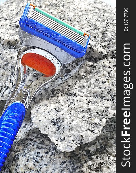 Razor on stone background with water drops in studio