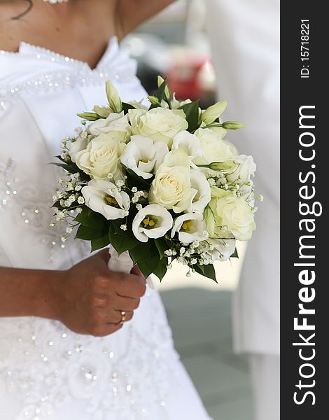 Bride in white dress holding her wedding bouquet in hand with engagement ring