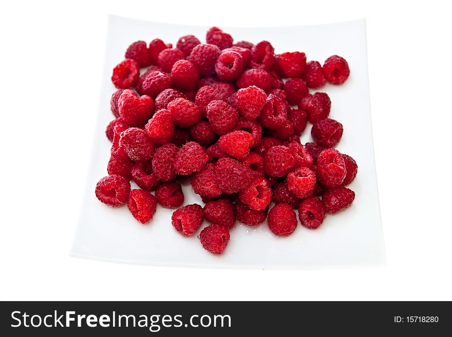 A heap of red raspberries on plate. Isolated on white