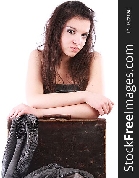 Beautiful brunette girl leaning on an old suitcase isolated on white. Beautiful brunette girl leaning on an old suitcase isolated on white