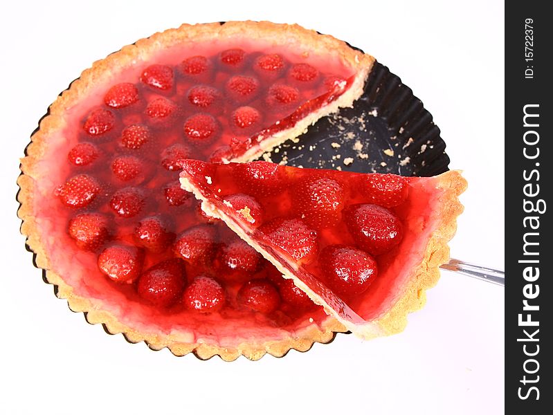 Strawberry Tart in a tart pan with a slice of it cut out on a white background