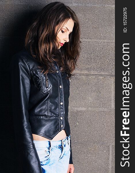 Beautiful sad model in a leather jacket against brick wall background. Beautiful sad model in a leather jacket against brick wall background