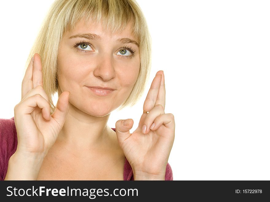 Beautiful young woman with fingers crossed over white background