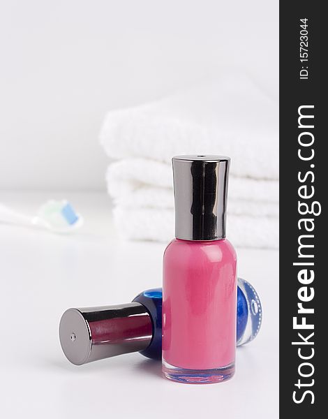 Nail polish placed in front of a white towel and a toothbrush.