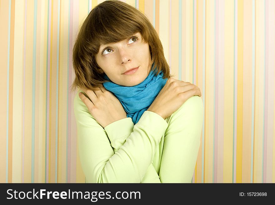 Beautiful young woman thinking. Home furnishings, arms crossed